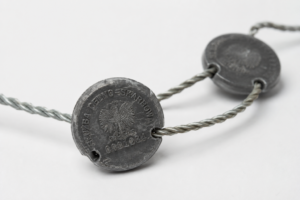 Close-up of a metal coin necklace: round discs threaded on a twisted wire chain, with an eagle design visible on the front.